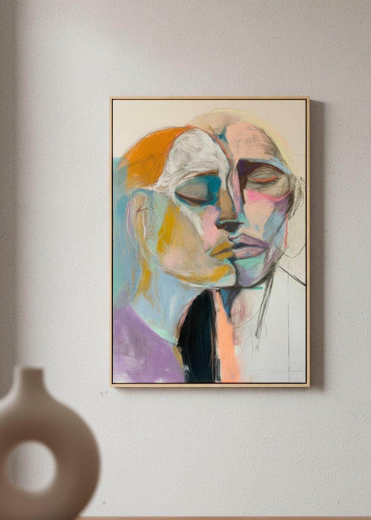 “Lovers” canvas print featuring two abstract faces merging in soft pastel tones, displayed in a minimalist room with neutral decor.