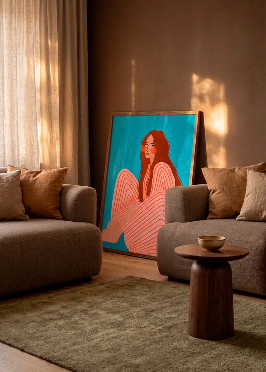 Serene Striped Woman by Bea Müller art print featuring a seated woman in a pink striped outfit against a vivid turquoise background, displayed in a wood frame in a warm, sunlit living room.