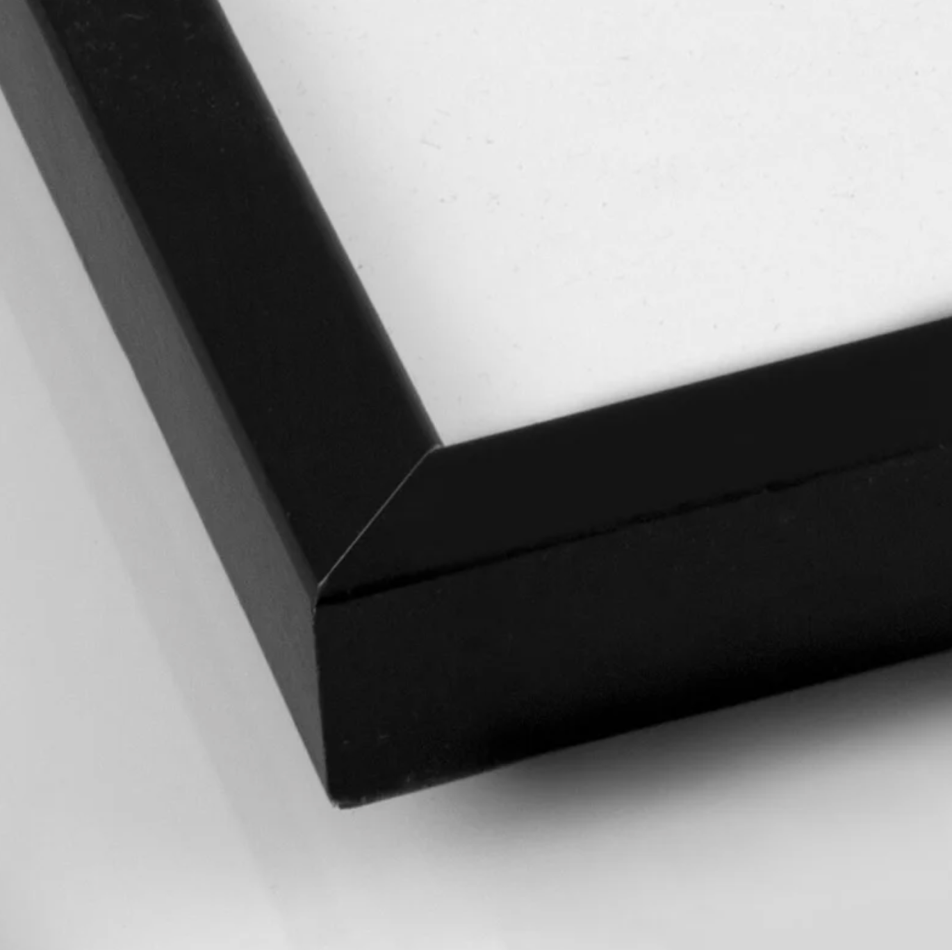 Close-up of the corner and material of a black wooden picture frame.