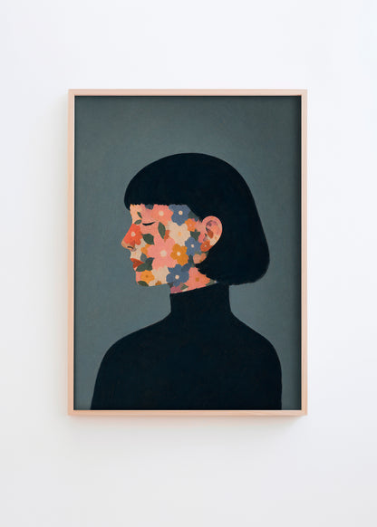 A Face I Once Knew poster featuring a woman’s profile with colorful flowers in muted pink, orange, blue and green tones on a dark blue-grey background, framed in light oak for a modern Scandinavian look.