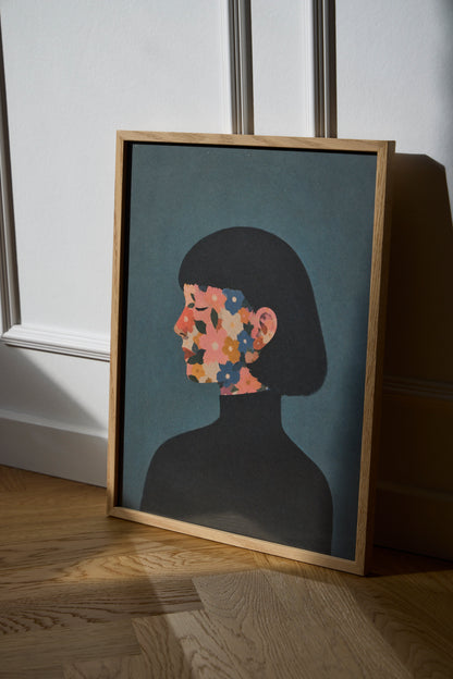 A Face I Once Knew poster featuring a woman’s profile with colorful flowers in muted pink, blue, orange and green tones, styled in a modern Scandinavian interior with an oak frame.