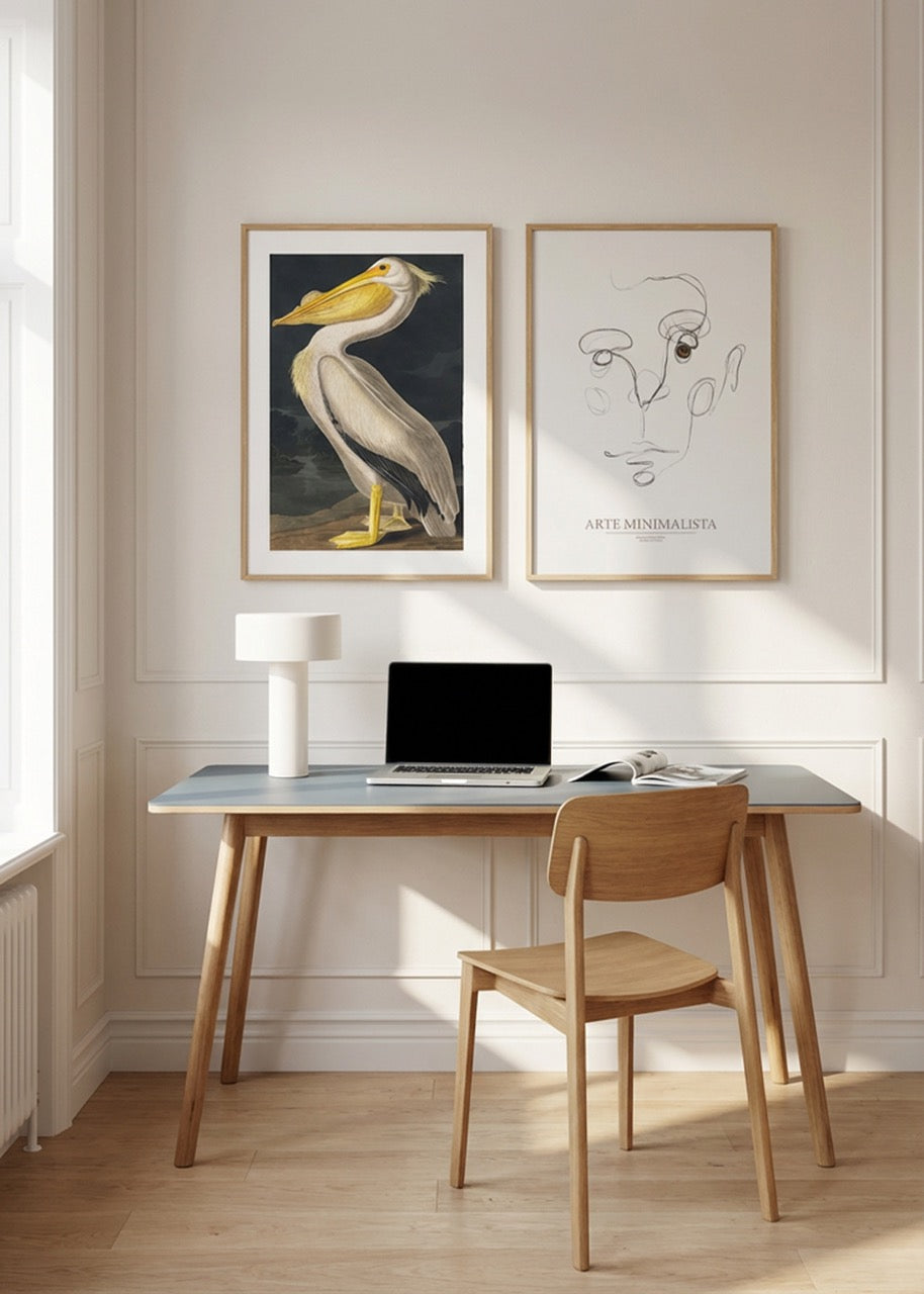 Pelican art print and minimalist line face poster in oak frames styled above wooden desk in bright Scandinavian home office.