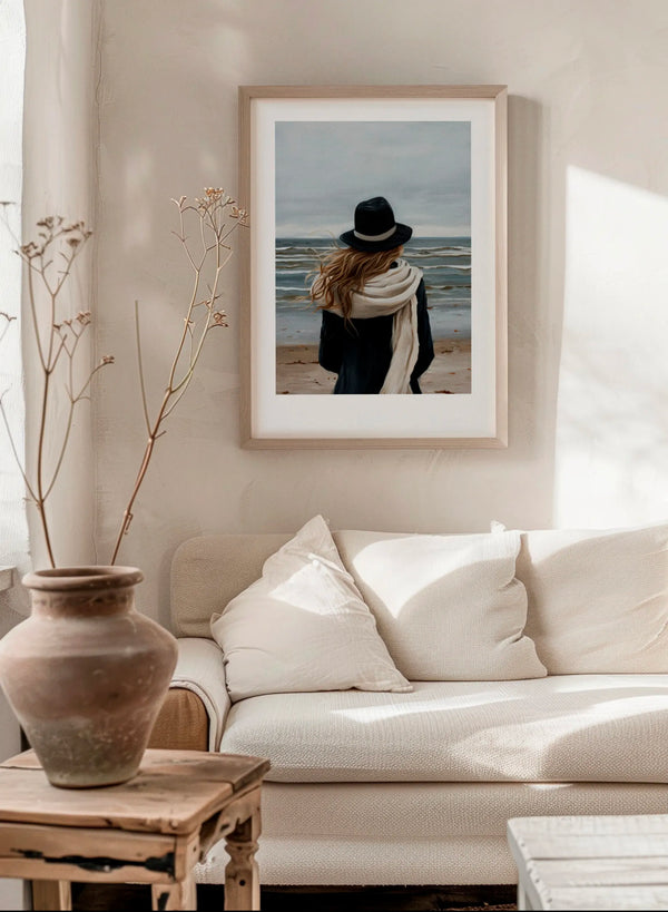 A Walk By The Sea poster in a modern Scandinavian living room with soft beige tones, neutral sofa and natural wood furniture, featuring calm blue, grey and sand coastal colors.