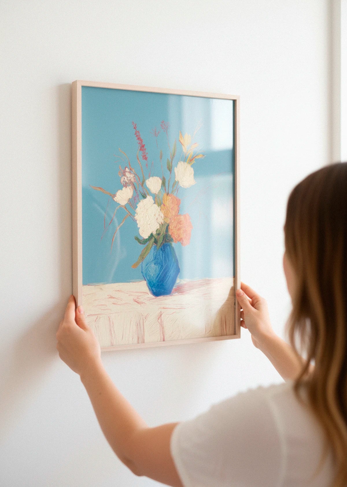 A framed floral poster titled Centerpiece being hung on a white wall, captured in soft natural light.