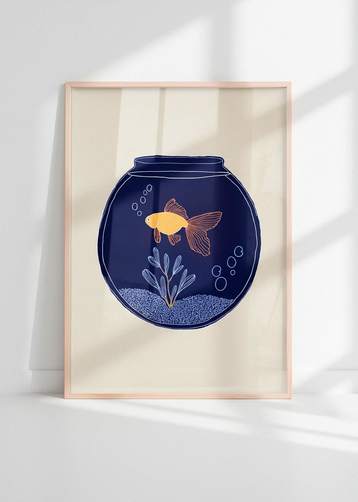 The Fishy poster with a yellow fish in a navy bowl, framed in light wood and displayed in bright natural light.