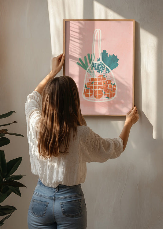 Fruit N Veg poster by Bea Muller being hung on the wall, showing a soft illustrated fruit motif in warm colours