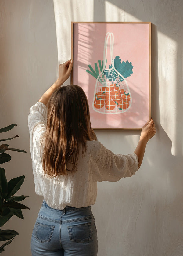 Fruit N Veg poster by Bea Muller being hung on the wall, showing a soft illustrated fruit motif in warm colours
