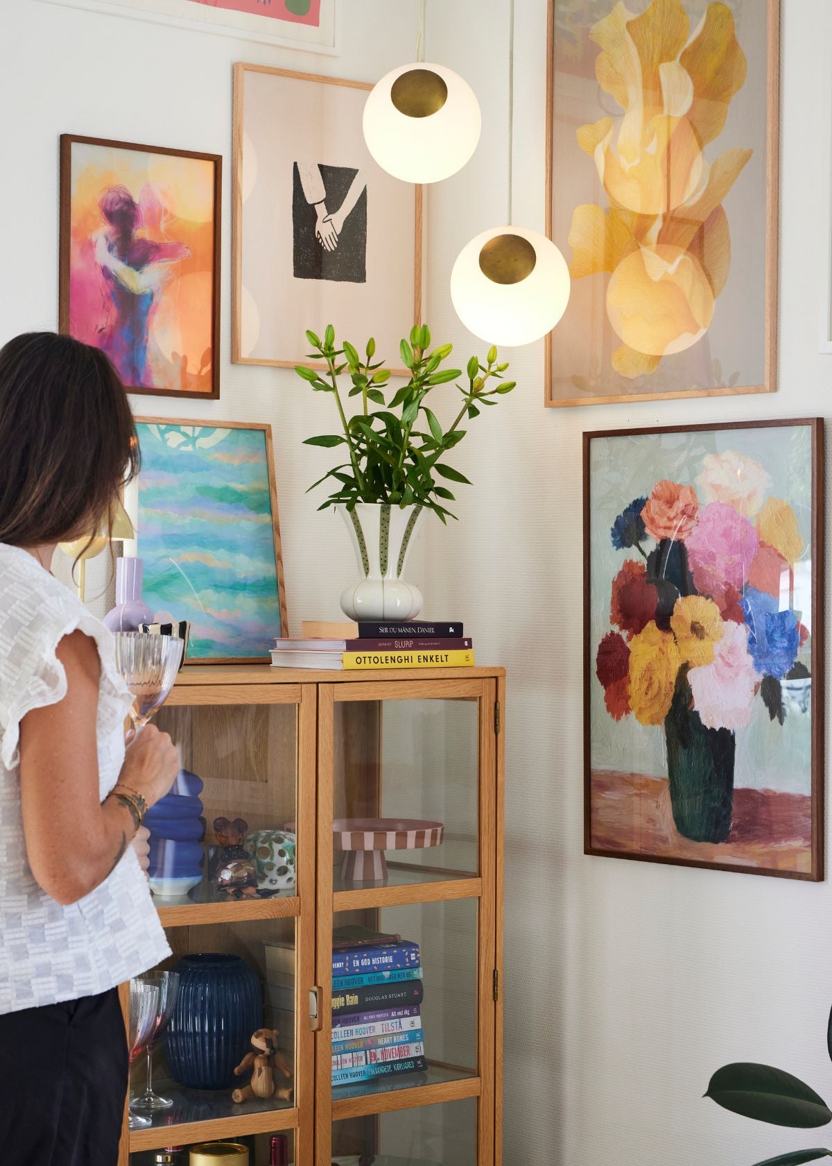 Scandinavian home gallery wall featuring pastel and abstract posters framed in oak, styled with modern decor and bookshelf.