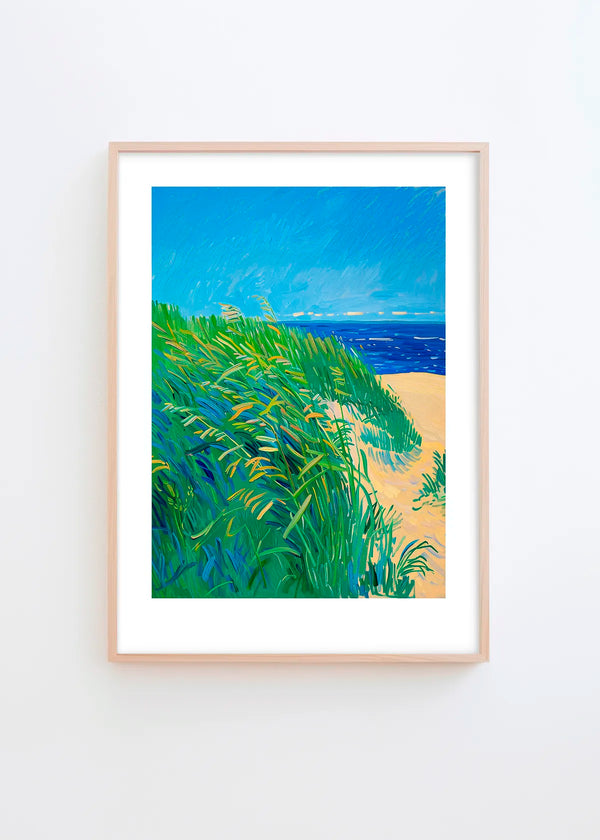 Lime Grass poster in a minimalist Scandinavian interior with light grey wall and natural wood frame, featuring vibrant green grass, sandy beige and deep blue coastal tones.