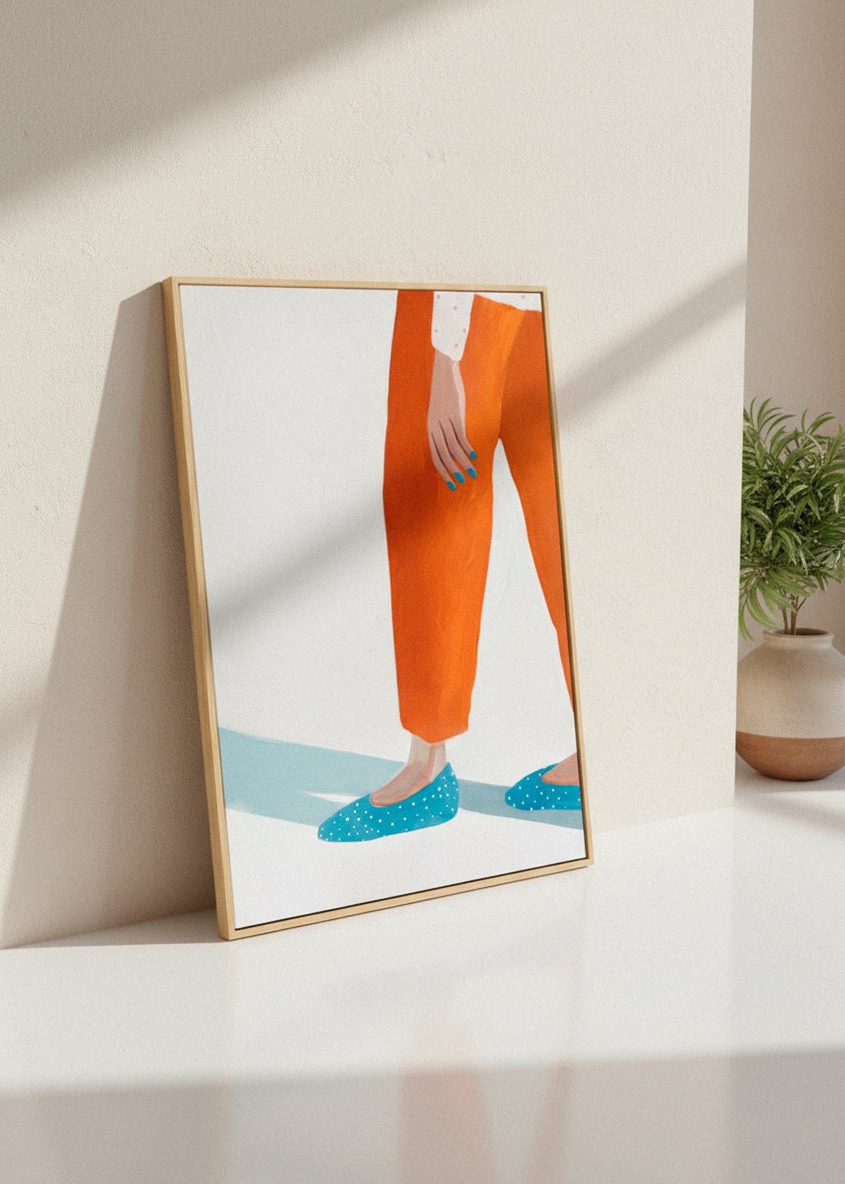 “Moody Nails” canvas print showing a cropped figure in orange trousers and blue dotted shoes, leaning against a light beige wall.