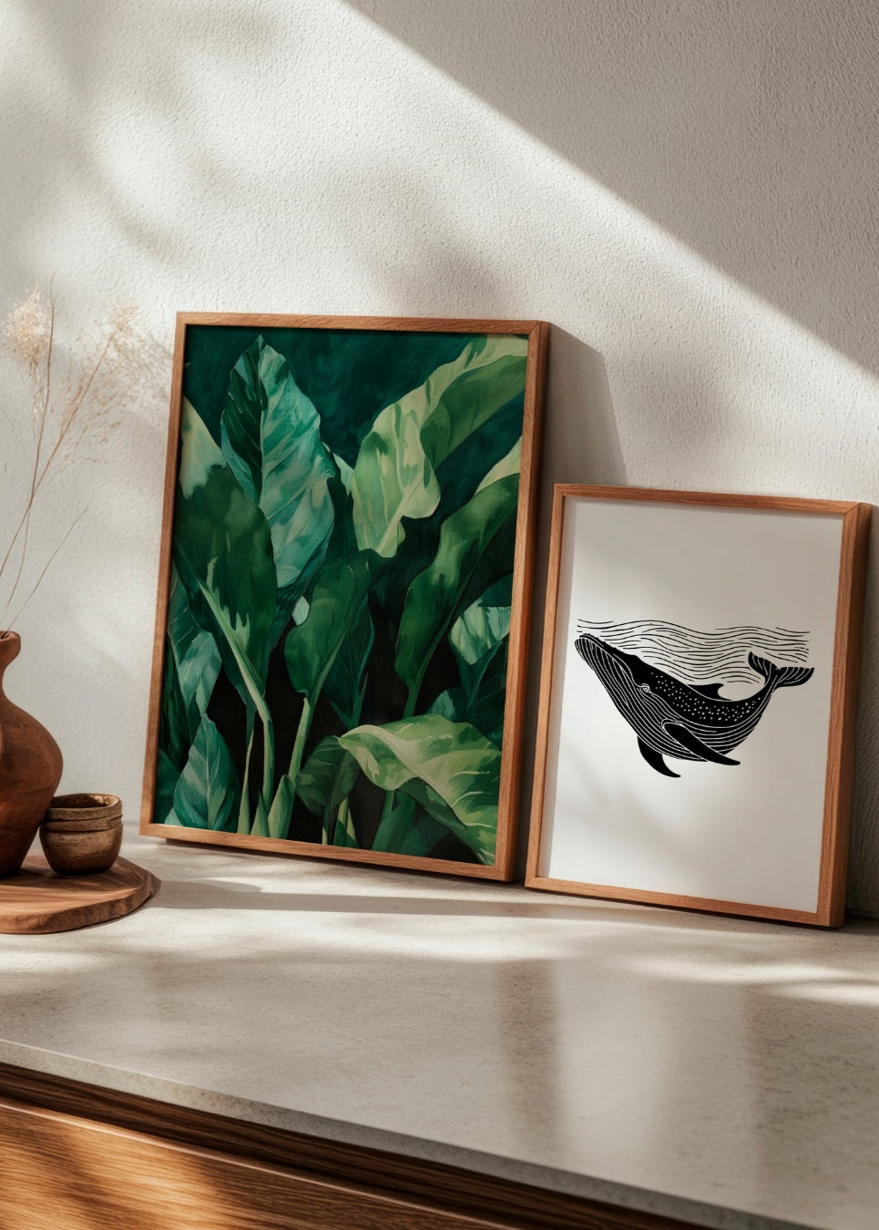 Minimalist whale illustration and lush green plant poster side by side in a bright Scandinavian-inspired room.