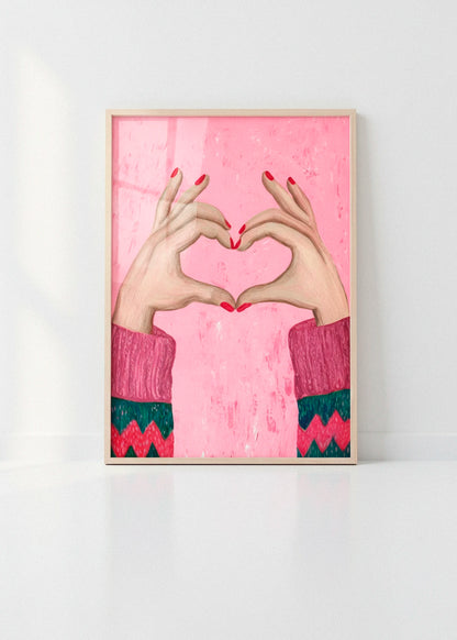 Sweater Love art print with pink background and heart-shaped hands, photographed in a bright minimalist interior with clean white walls.