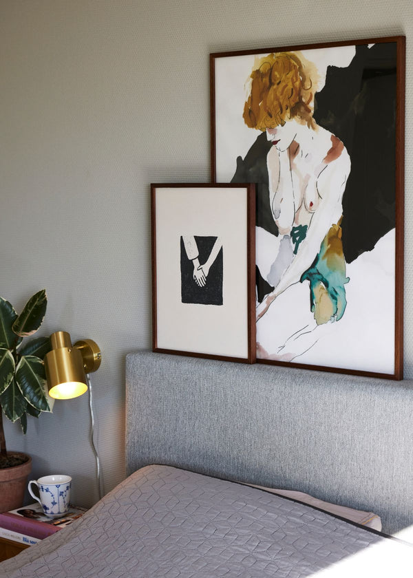 Togetherness and Femme Fatale posters styled together in wooden frames, adding contrast and personality to a Scandinavian bedroom interior.