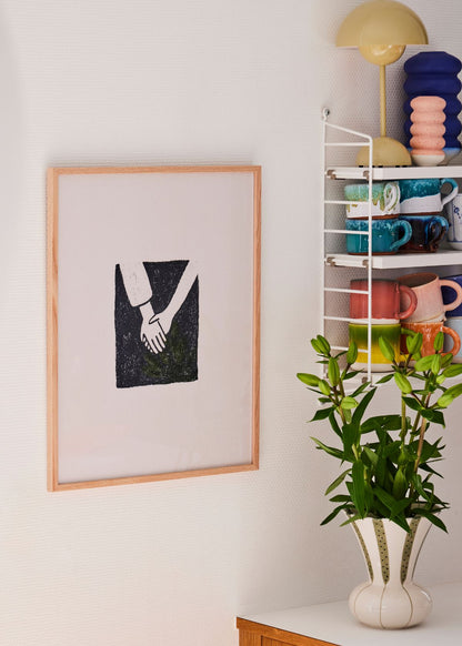 Togetherness poster with minimalist hand motif in a wooden frame, surrounded by vibrant flowers and Scandinavian ceramics.