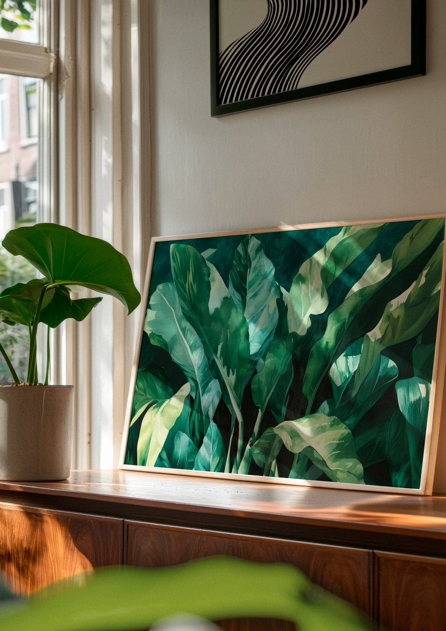 Plant poster leaning against a wall in a sunlit space – A lush botanical print adding a fresh, natural vibe to a modern home with wooden and earthy tones.